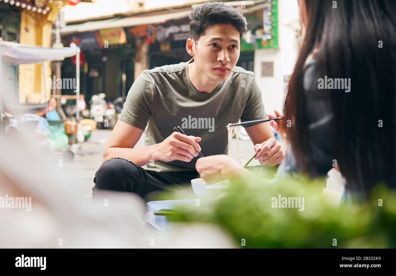 Young couple eating vietnamese food in the city street Stock Photo