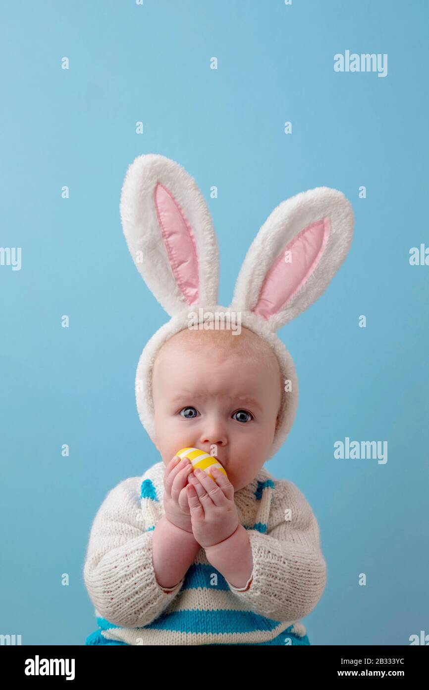 Cute baby wearing easter bunny ears playing with an easter egg Stock
