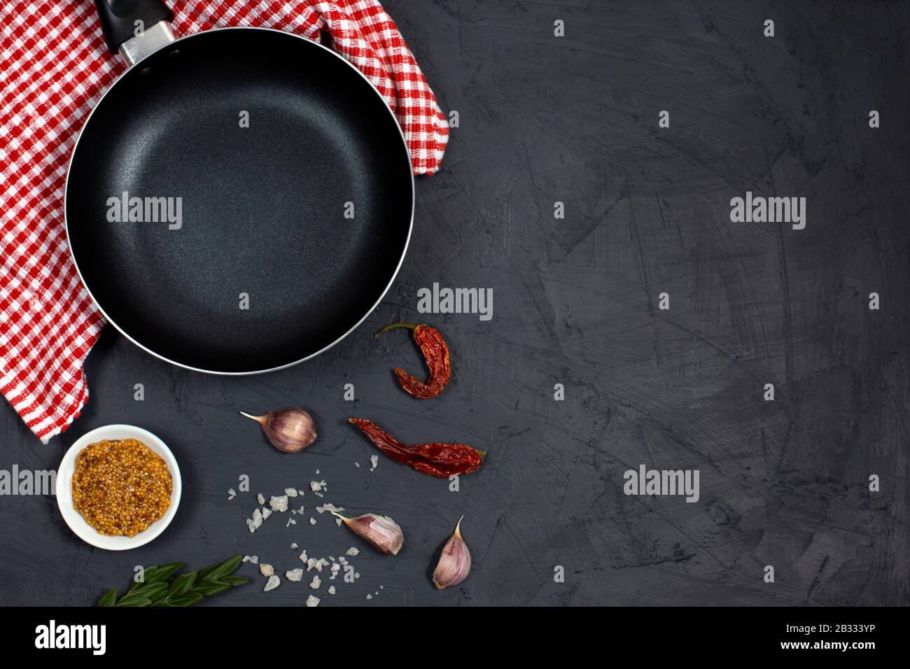 Food cooking background with black frying pan or skillet, spices and ...