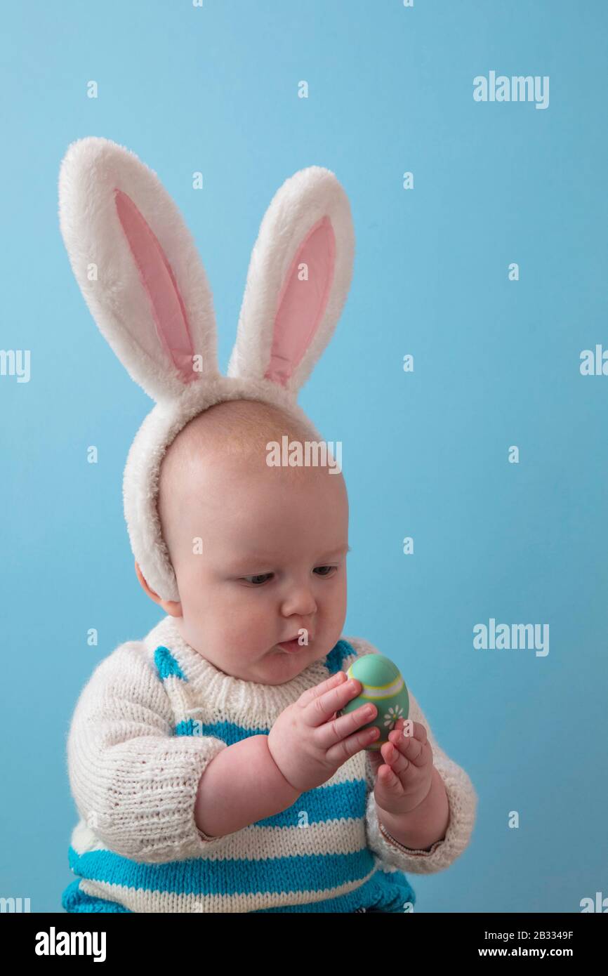 Cute baby wearing easter bunny ears playing with an easter egg Stock