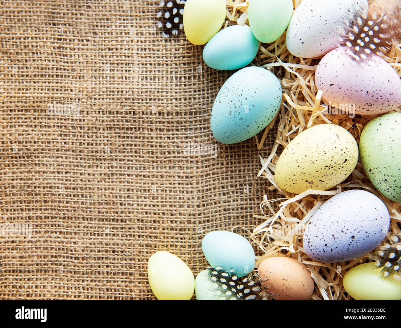 Easter eggs on a sackcloth and straw . Happy Easter  multicolored  easter eggs. Background with easter eggs. Flat lay, top view. Stock Photo