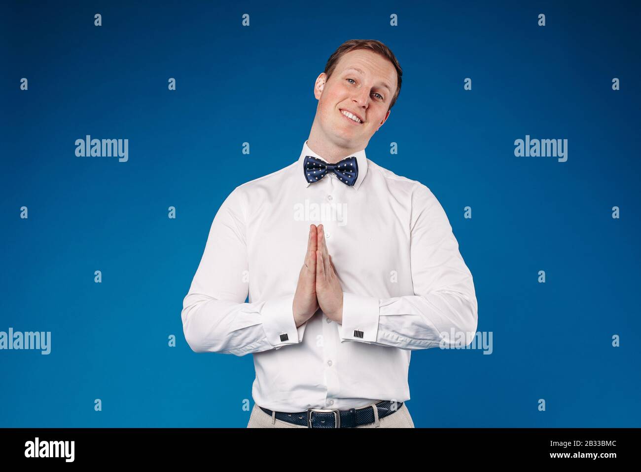 Man wearing white shirt and bow tie showing sign of pistol Stock Photo