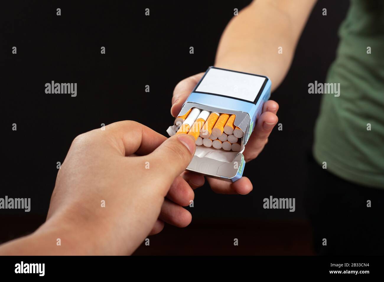 suggest cigarettes. hand takes from a pack harm from tobacco use  close-up on a dark background. Stock Photo