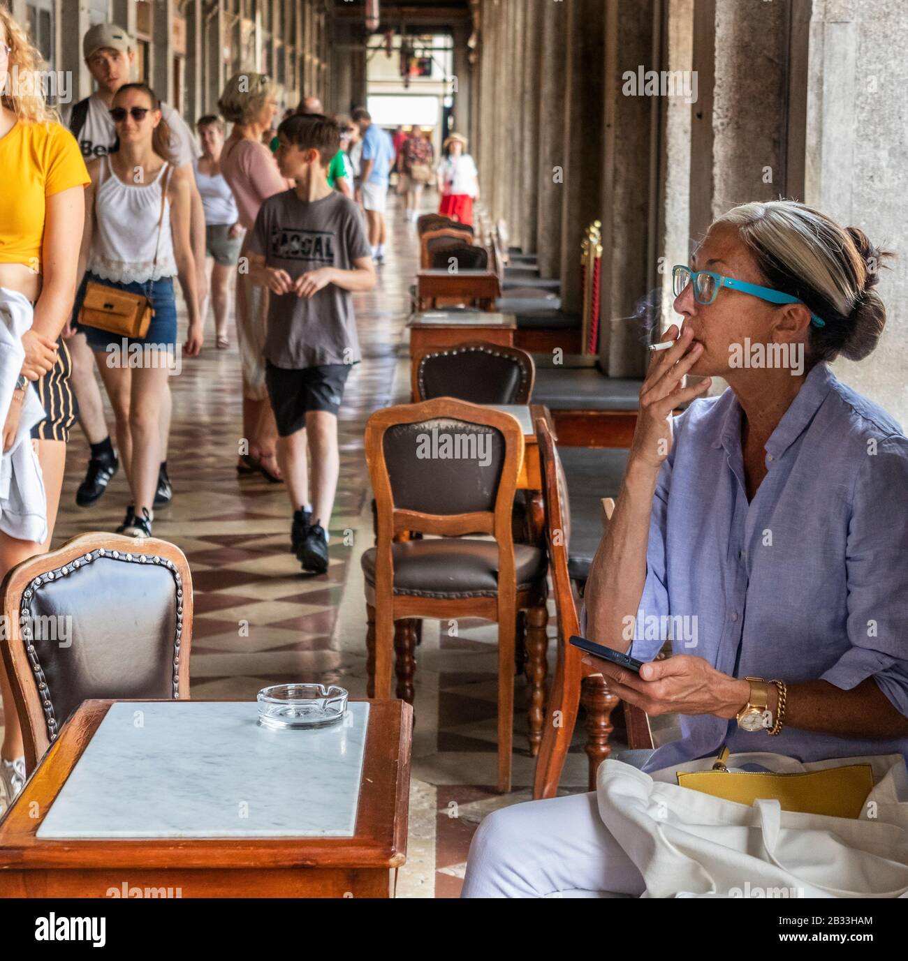 Trendy female smoking a cigarette at Caffe Florian, the oldest cafe in