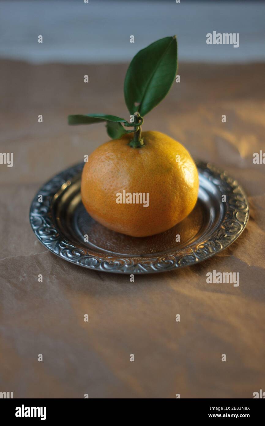 Mandarine orange on a metal plate over parchment paper Stock Photo Alamy
