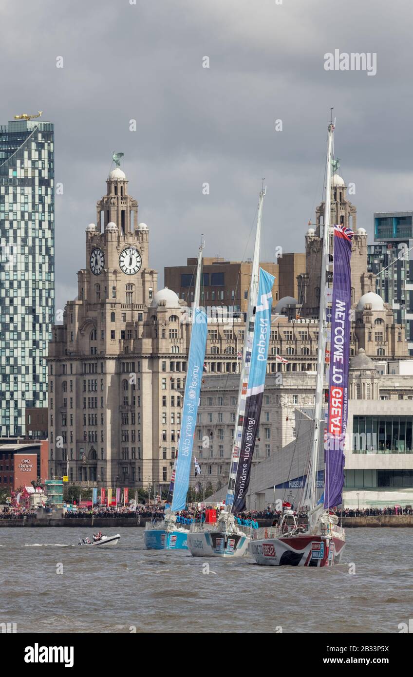 Yachts pass the Three Graces on Liverpool's waterfront during the Parade of Sail before the start of the Clipper 2017–18 Round the World Yacht Race Stock Photo