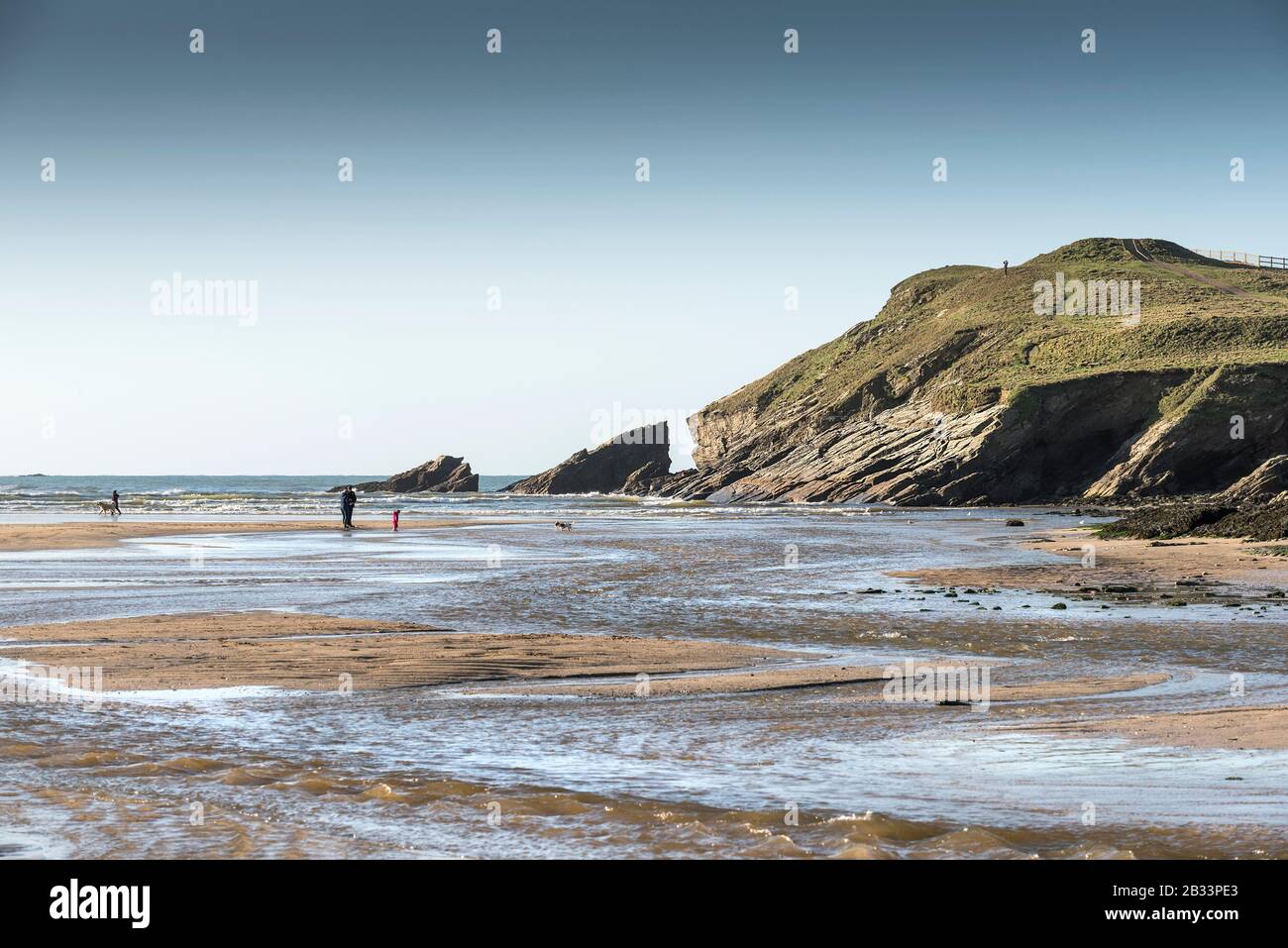 Porth Beach at low tide and the remains of a Bronze Age Barrow on