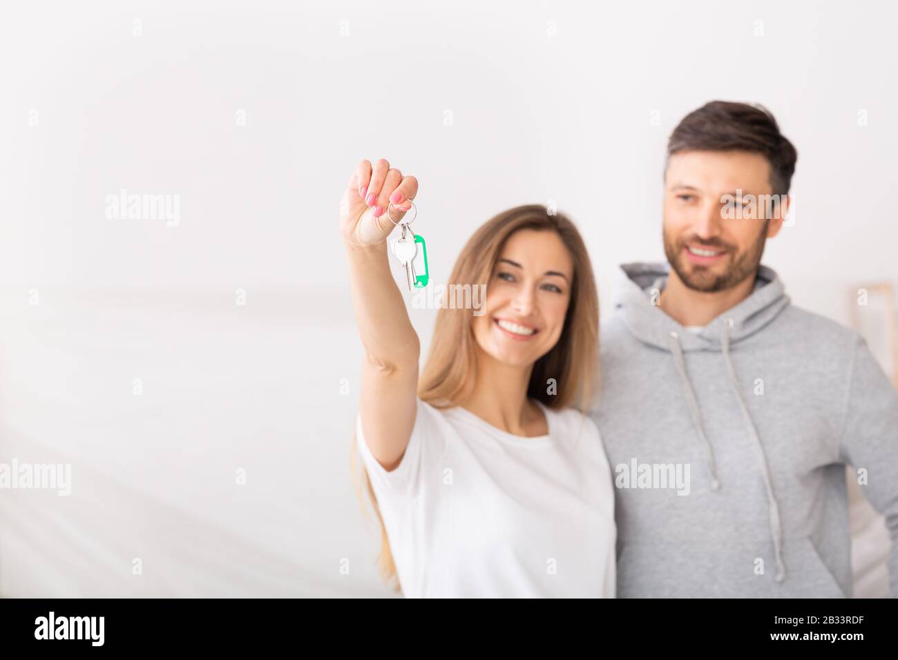 Young smiling couple showing keys of new home Stock Photo - Alamy