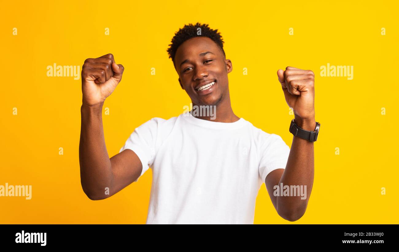 Young cheerful african guy moving dancing on yellow Stock Photo