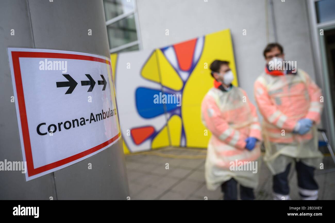 04 March 2020, Baden-Wuerttemberg, Stuttgart: Volunteers of the German Red Cross (DRK) are standing in front of the corona outpatient clinic of the Klinikum Stuttgart in the Katharinenhospital, to which a sign points. Patients can have themselves tested in the Corona Outpatient Clinic. Photo: Sebastian Gollnow/dpa Stock Photo