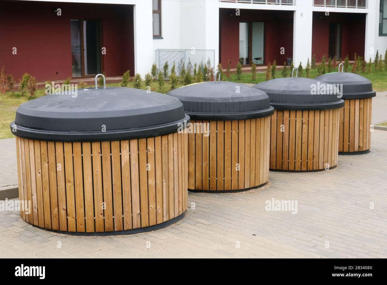 Big modern standard wooden trash bins are located near the public home