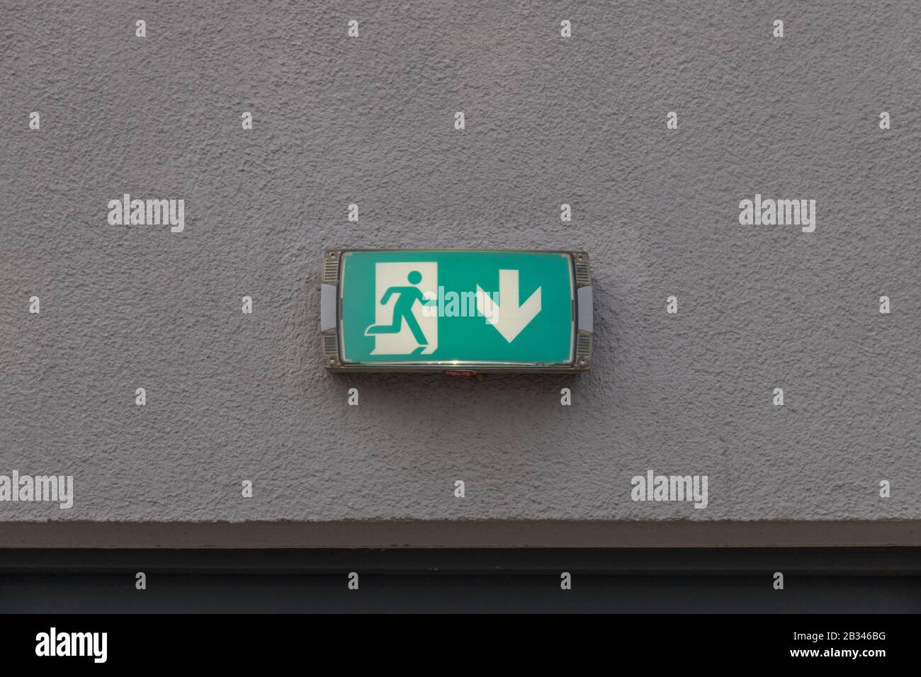 this sign on a wall shows the escape route with an arrow Stock Photo