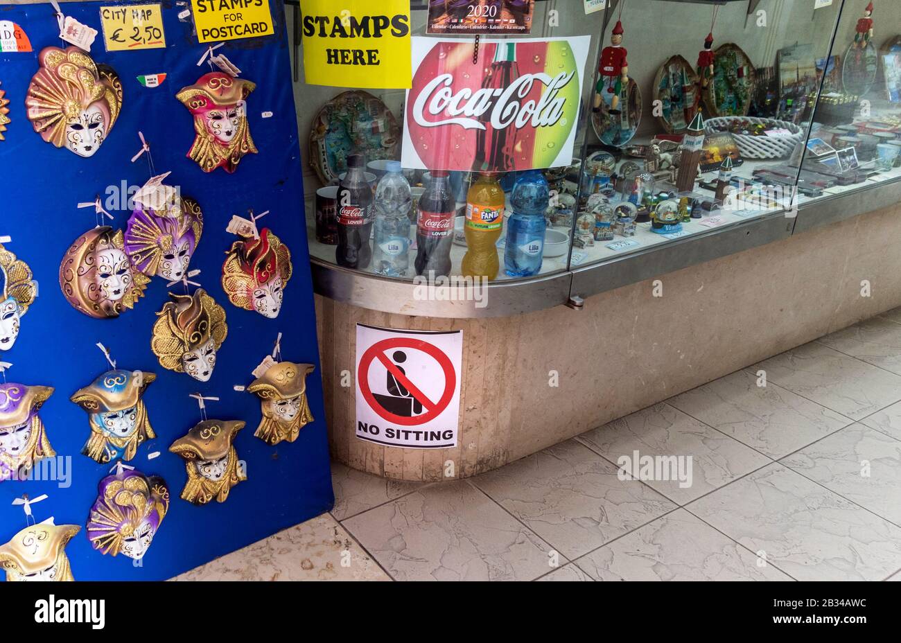 New laws in Venice Italy against tourists who behave badly. Fines will be issued, No sitting sign in front of shop window, Venice, Italy Stock Photo