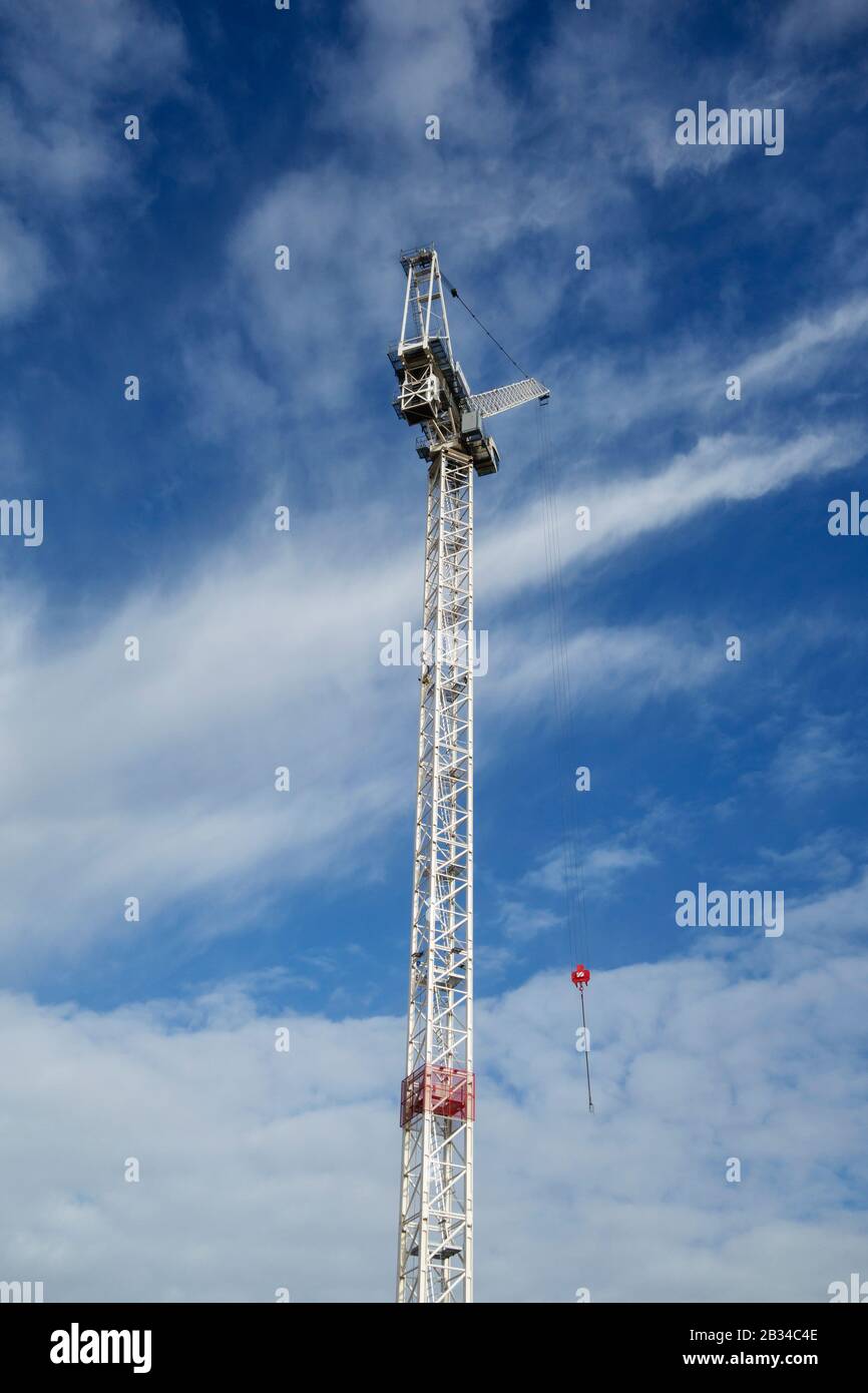 Looking up at a white tower crane against a blue sky with white clouds, central London, UK Stock Photo