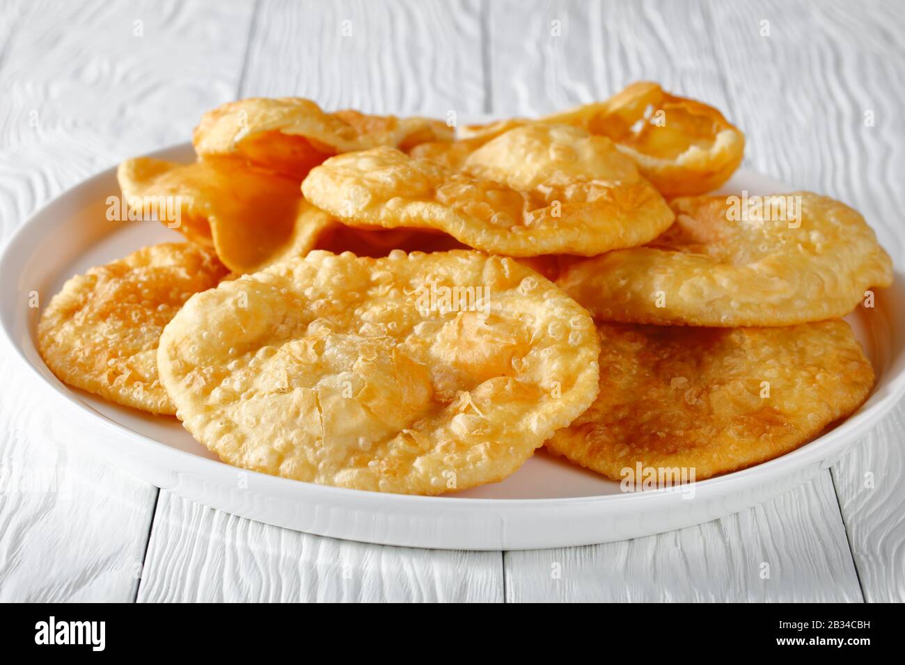 close-up of Bhatura, indian deep fried leavened bread on a white platter on a wooden table, horizontal view from above Stock Photo
