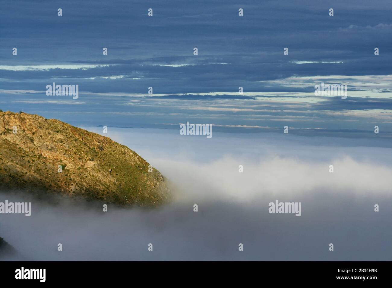 Hill covered with fog and a blue sky during daytime Stock Photo - Alamy