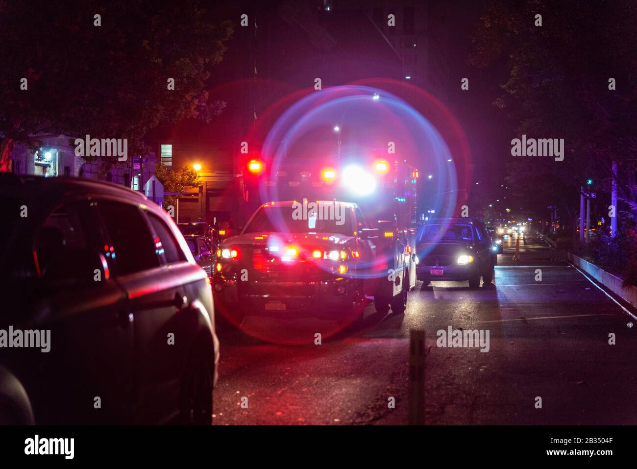 Red and blue ambulance car emergency lights on a street at night in