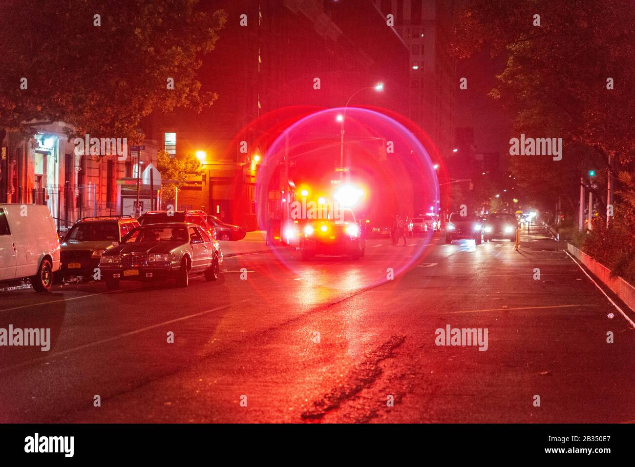 Red and blue ambulance car emergency lights on a street at night in