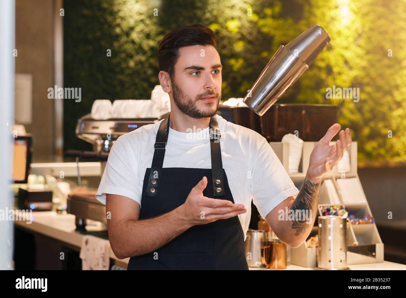 Bartender Using Shaker Making Cocktail Standing At Bar Counter Indoor