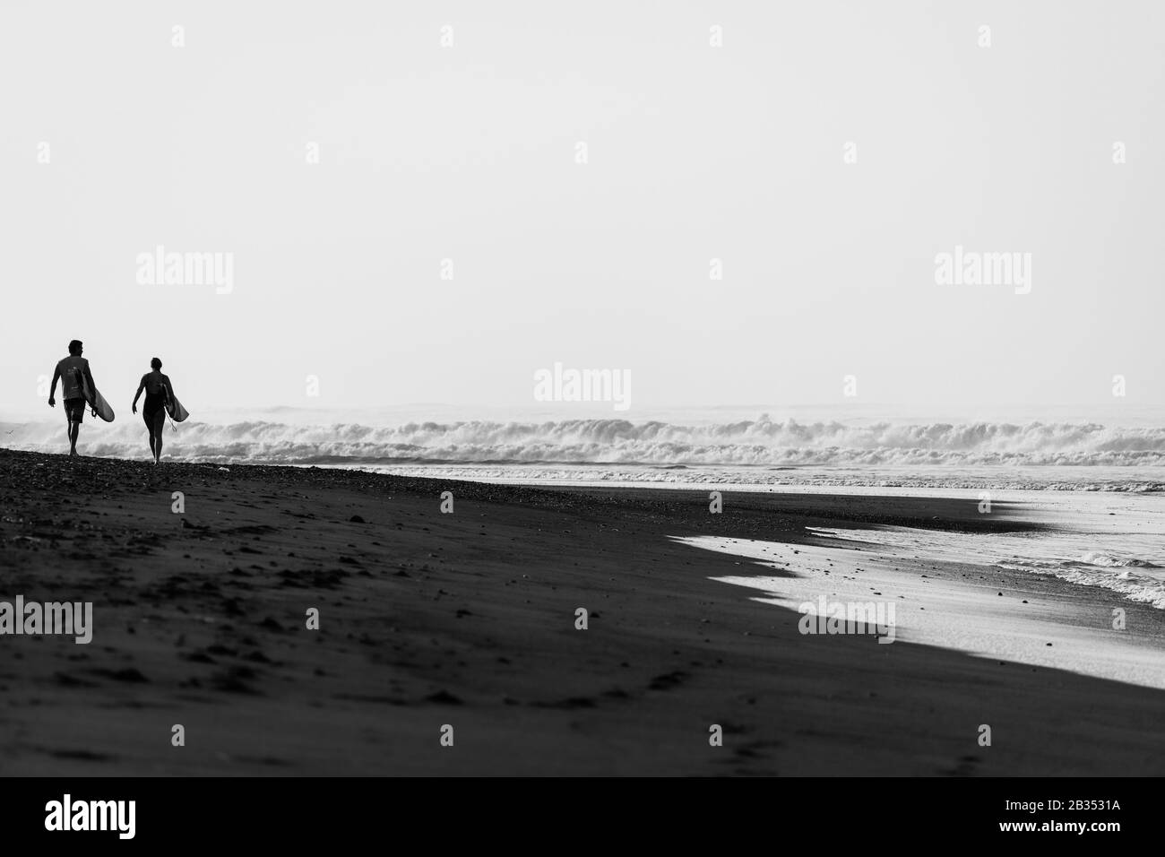 Beautiful scenery of surfers on an island beach at sunset - perfect for wallpaper Stock Photo