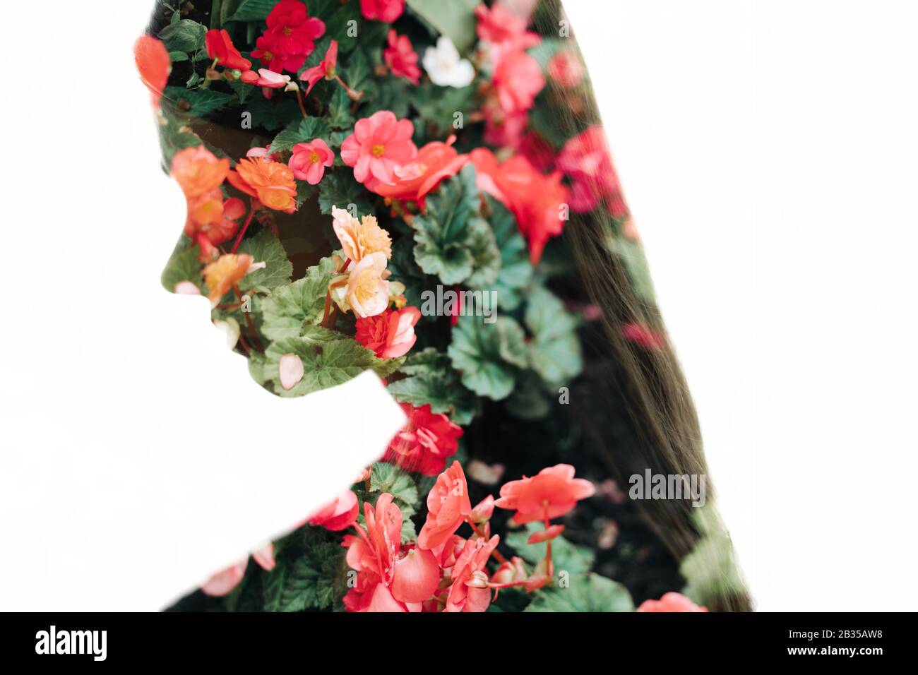 Portrait of pretty woman with long hair and summer flowers background (double exposure, tilt-shift lens blur) Stock Photo