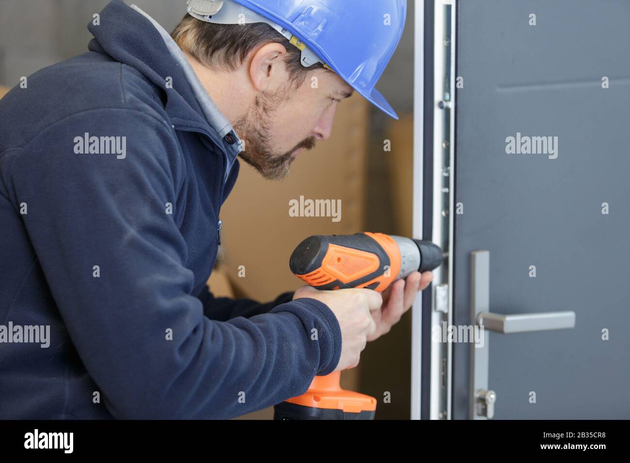 man drills a hole in a door Stock Photo Alamy