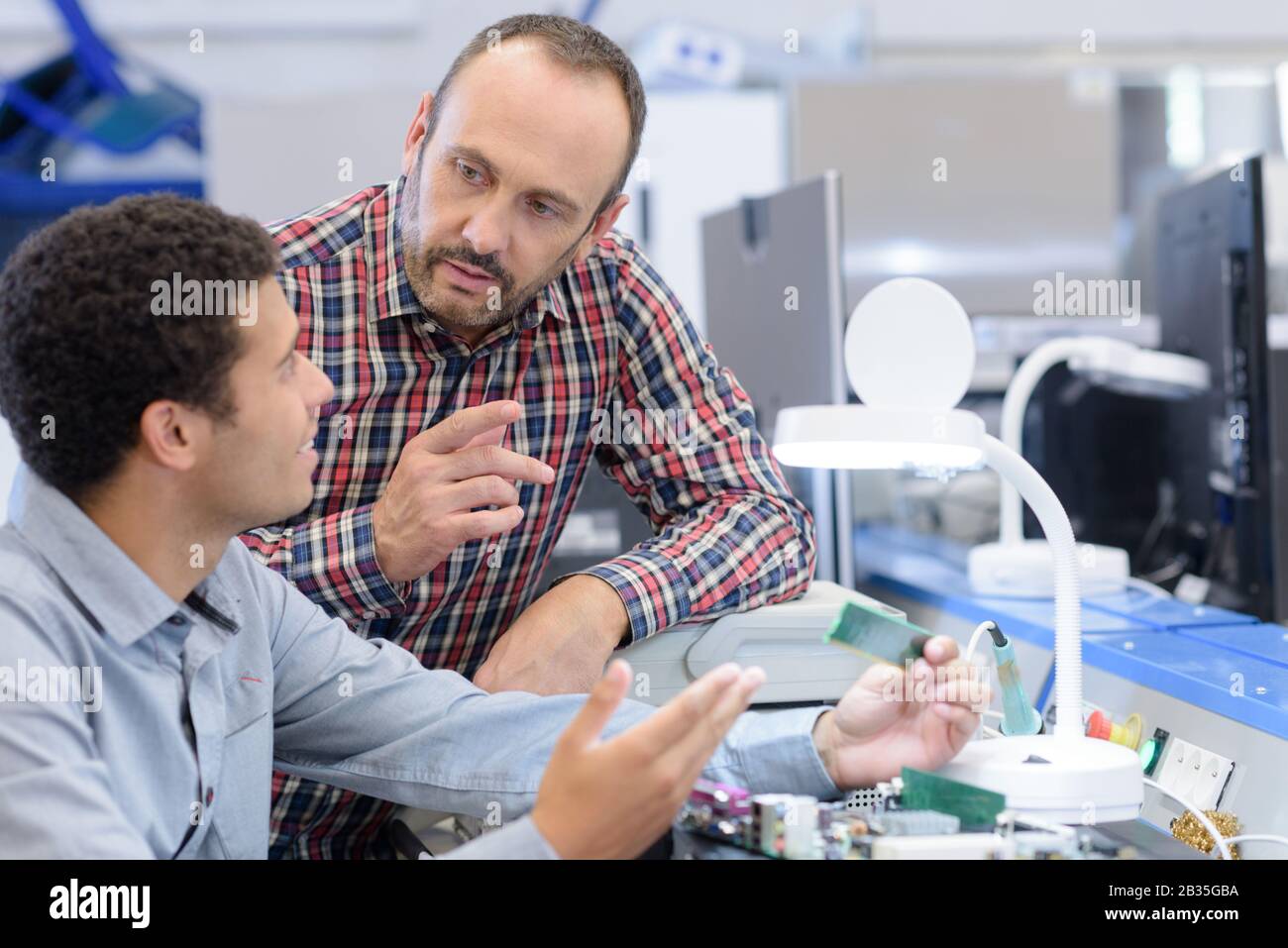 two technician examining a mechanical part in the workshop Stock Photo