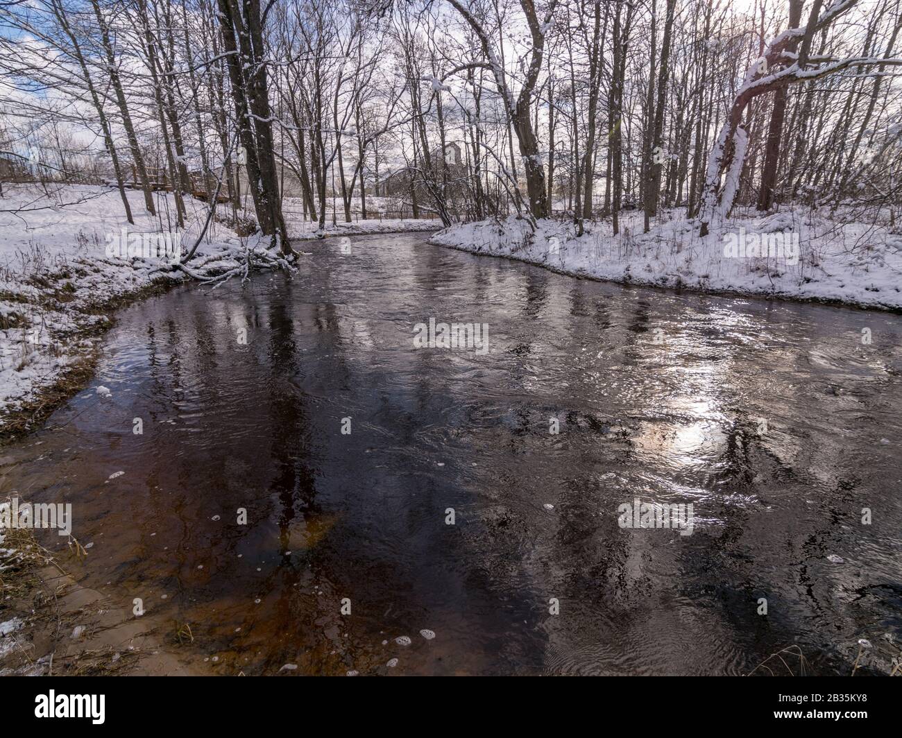 winter landscape with wild fast flowing river, snow covered land, lots ...