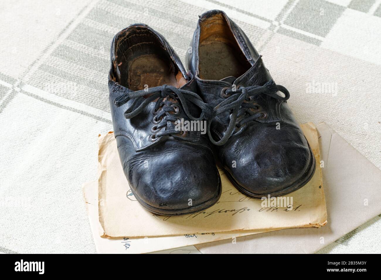 Remembrance of Childhood: Vintage Children's Shoes and Letters: a pair of old handmade children's shoes on old envelopes and textile background Stock Photo