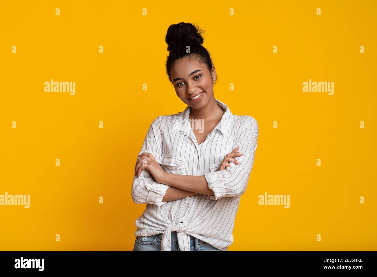 Beautiful Smiling Black Woman Posing With Folded Arms Over Yellow Background Stock Photo