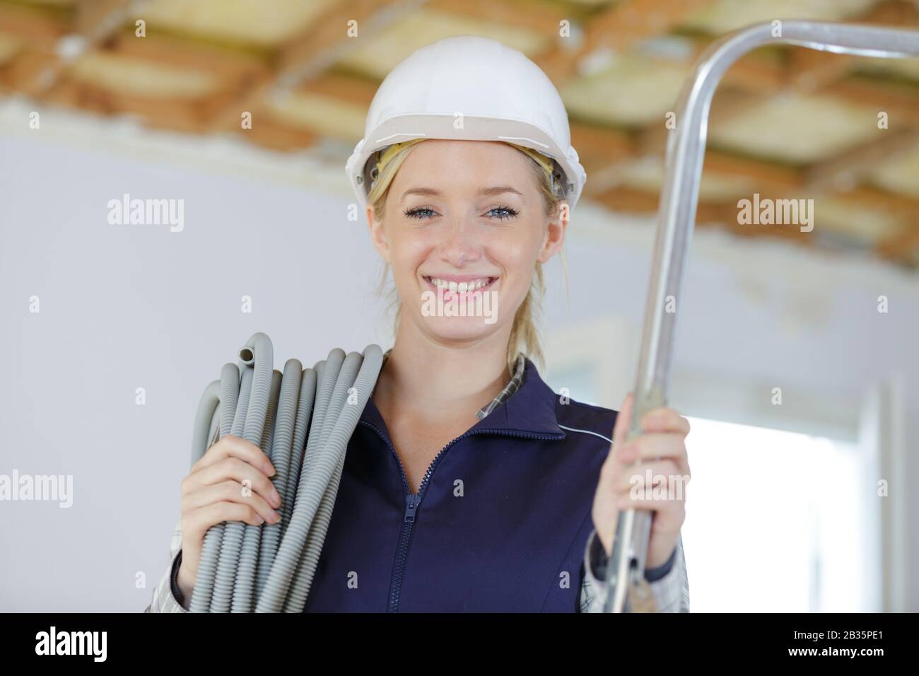 portrait of female builder carrying reel of cable Stock Photo