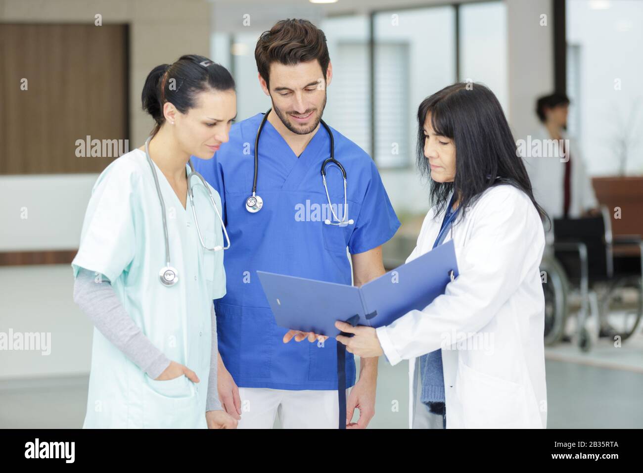three medical workers looking at folder and conferring Stock Photo