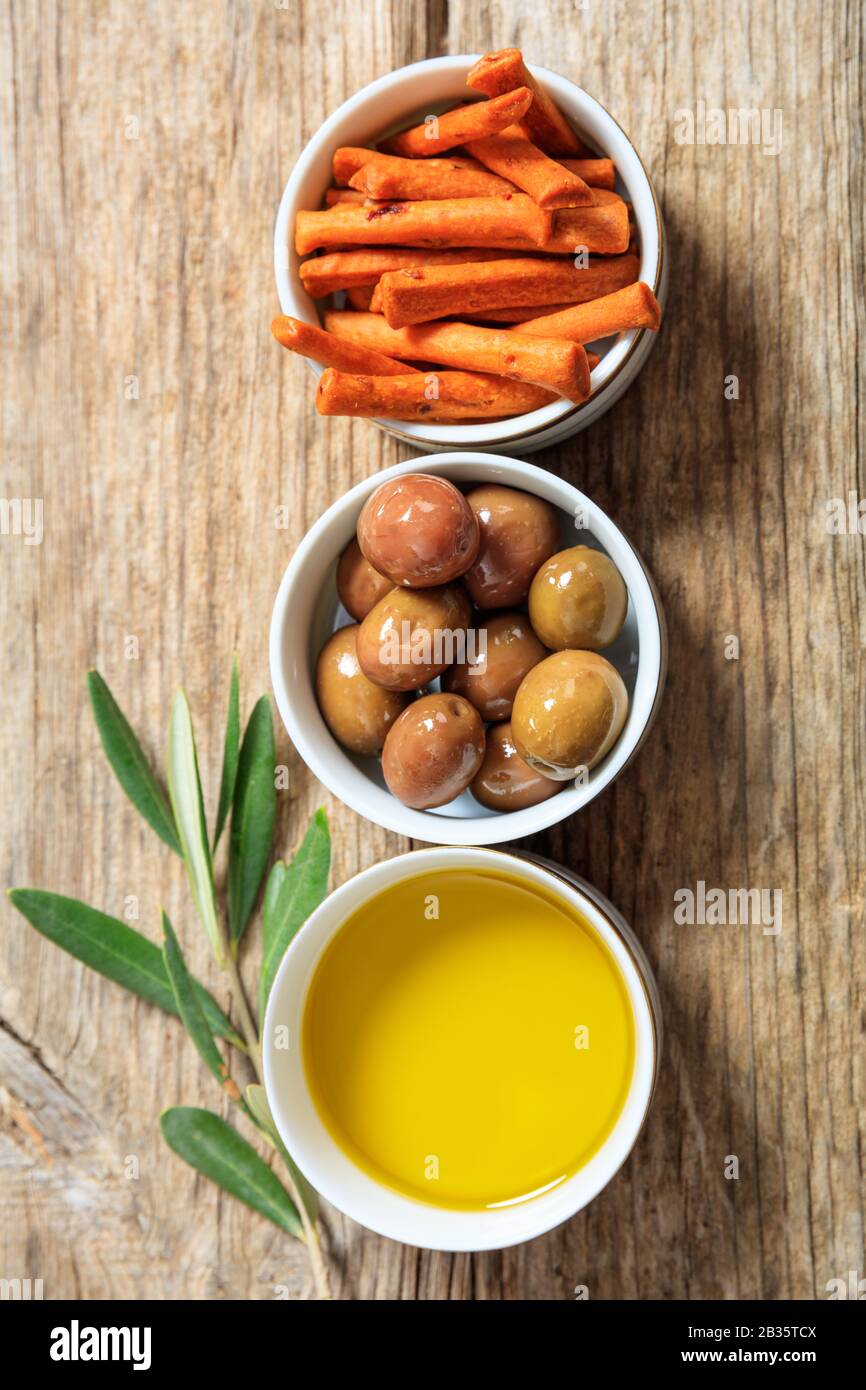 Olives and olive oil on wood table, top view. Mediterranean appetizers