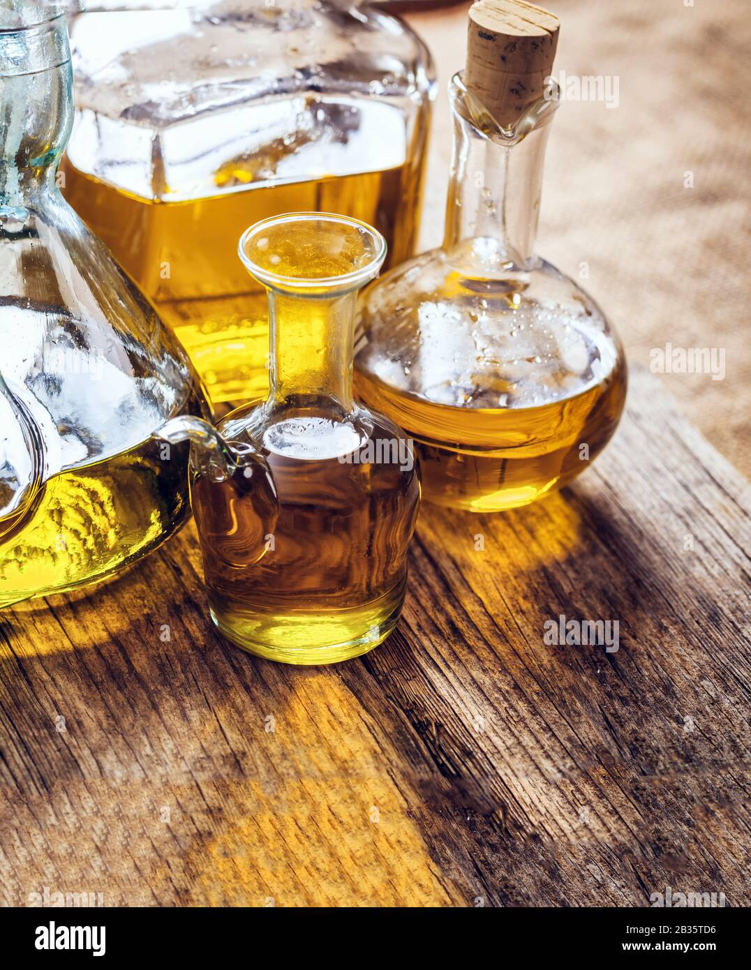 Olive oil bottles variety on a wooden table, closeup verical view. Assortment of extra virgin healthy olive oil on wood Stock Photo