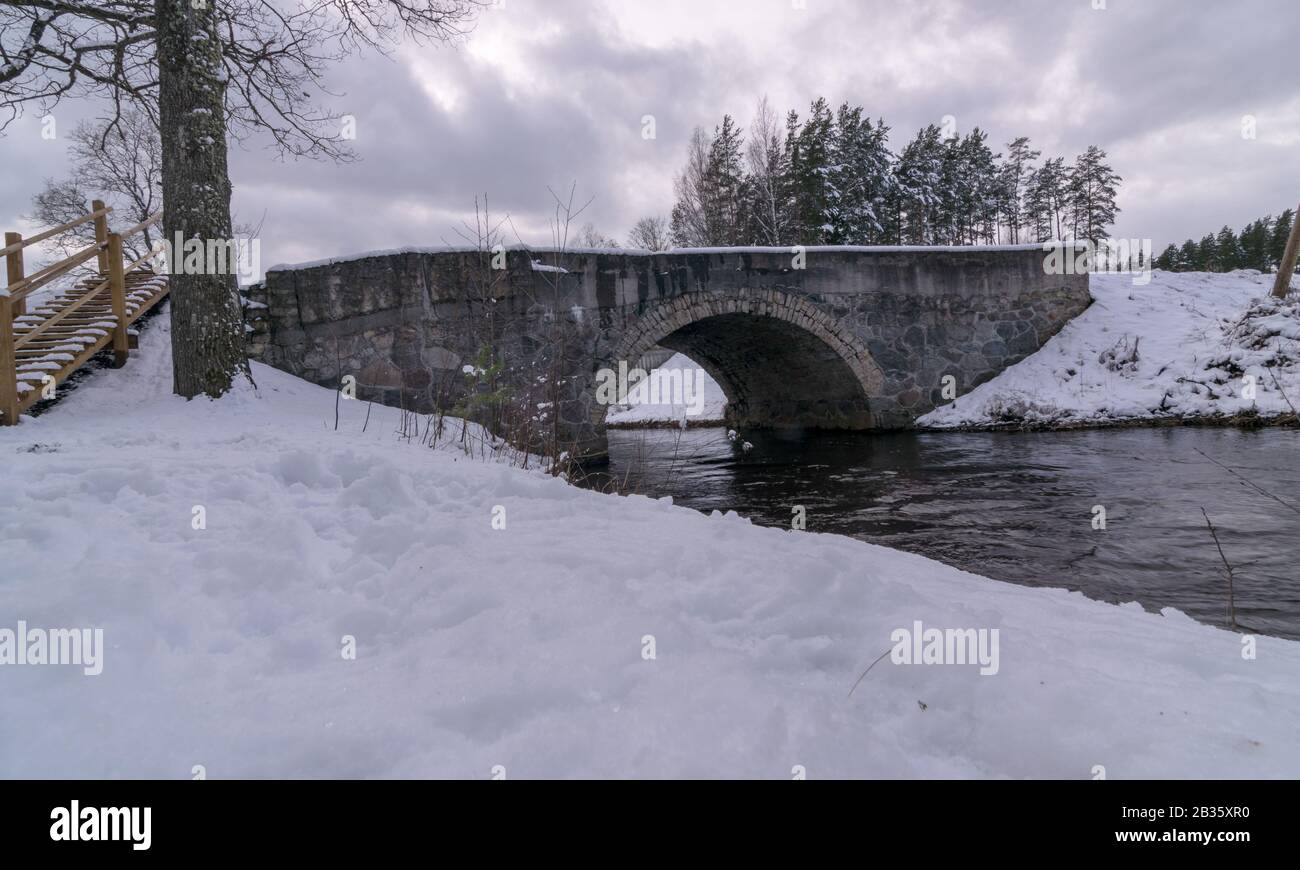 Winter Fast Bridge arched bridge over a fast flowing river, covered with snow Stock Photo ...