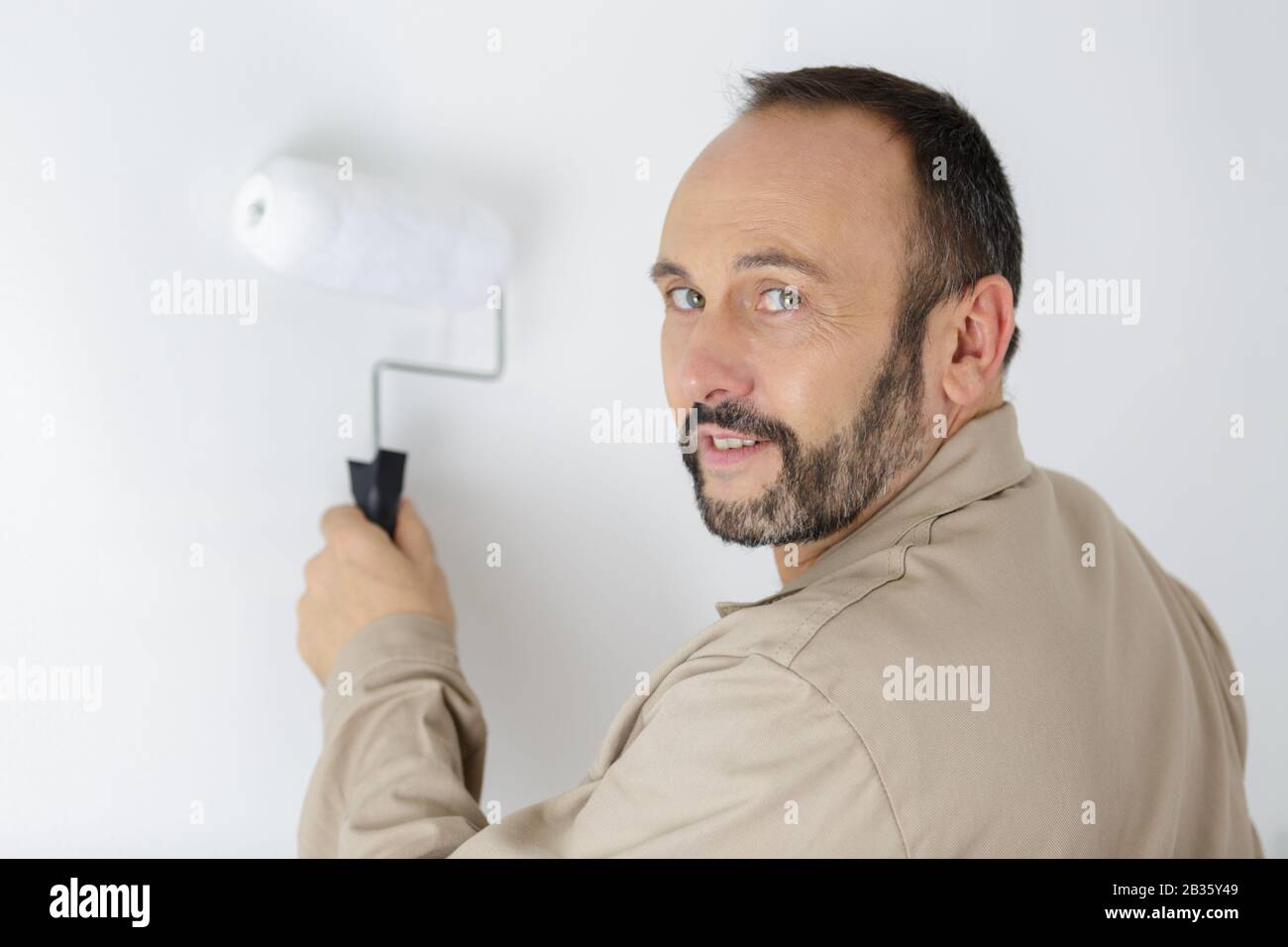 man painting wall with roller Stock Photo - Alamy