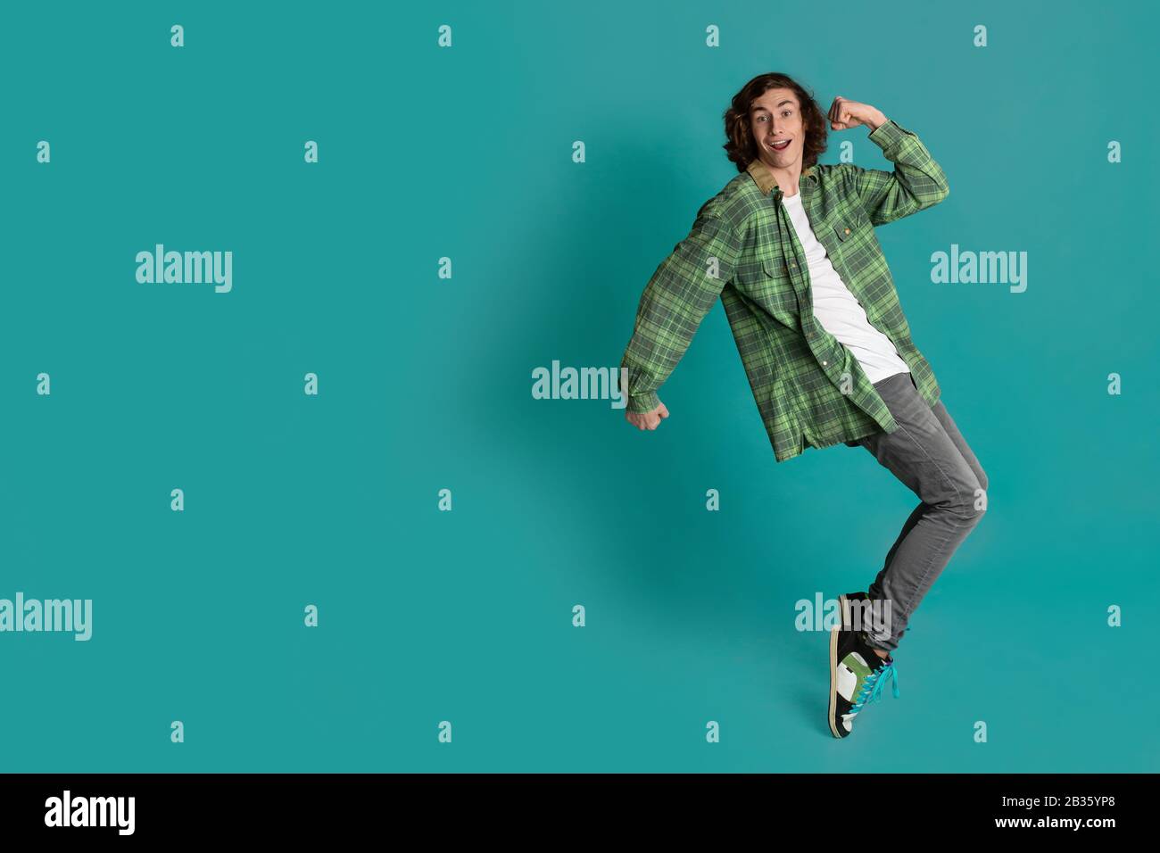 Cheerful young man standing on tiptoes against color background, empty space Stock Photo
