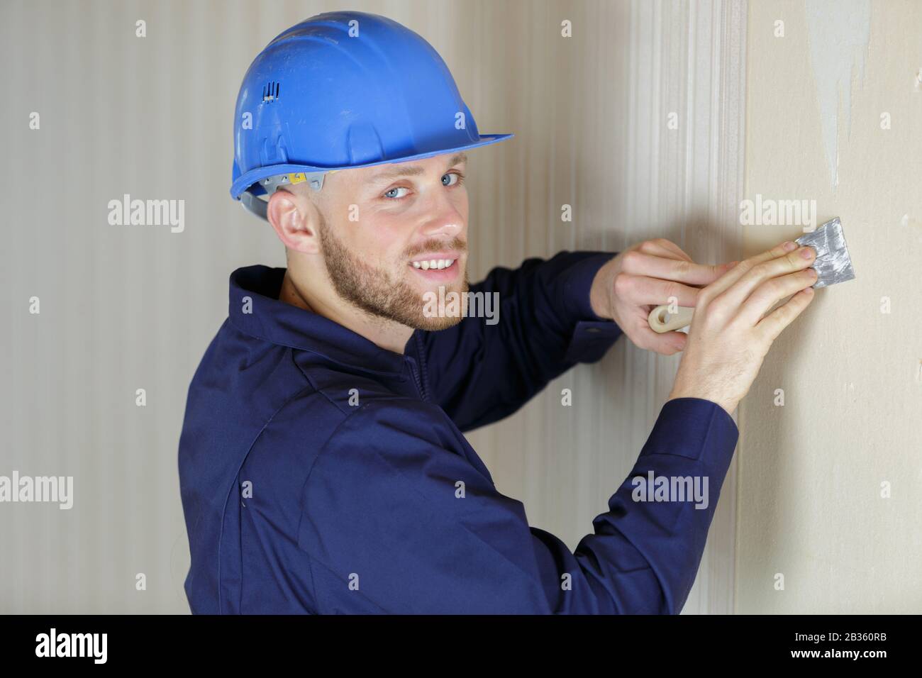portrait of a tradesman scraping wallpaper off the wall Stock Photo Alamy