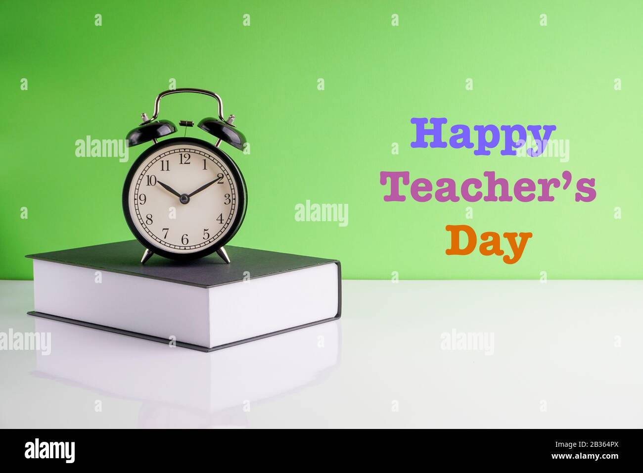 HAPPY TEACHERS DAY text, Alarm Clock and book on green background. Copy