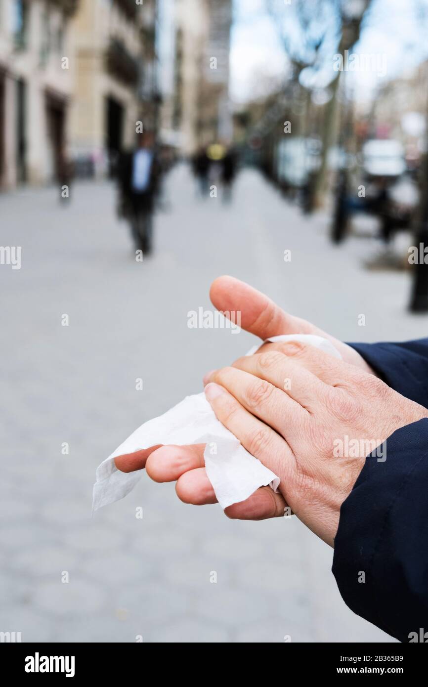 closeup of a caucasian man on the street disinfecting his hands with a wet wipe Stock Photo