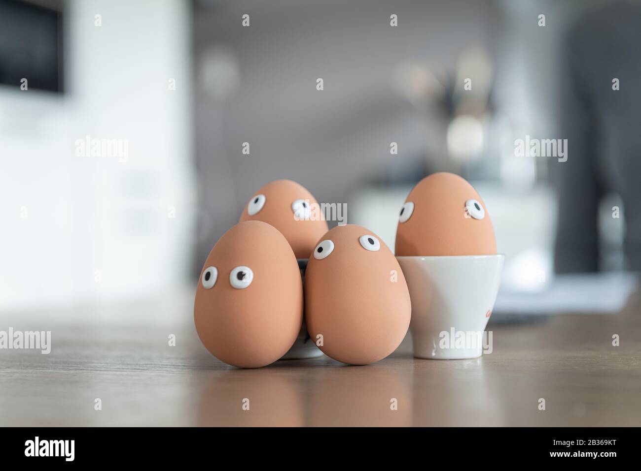 Cheerful easter eggs on the kitchen table, easter egg hunt, egg characters with funny faces, easter concept, kitchen in the background, easter theme, Stock Photo
