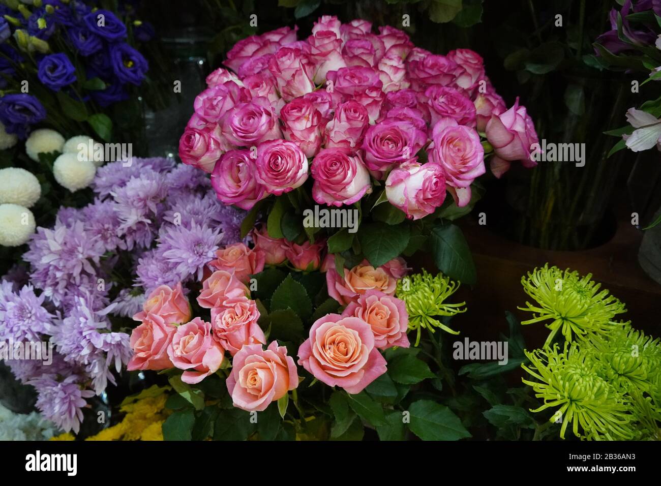 Bouquet of colorful roses and other different flowers at the entry to flower shop at farmers' market. Colorful peony, roses etc. Pots with flowers on Stock Photo