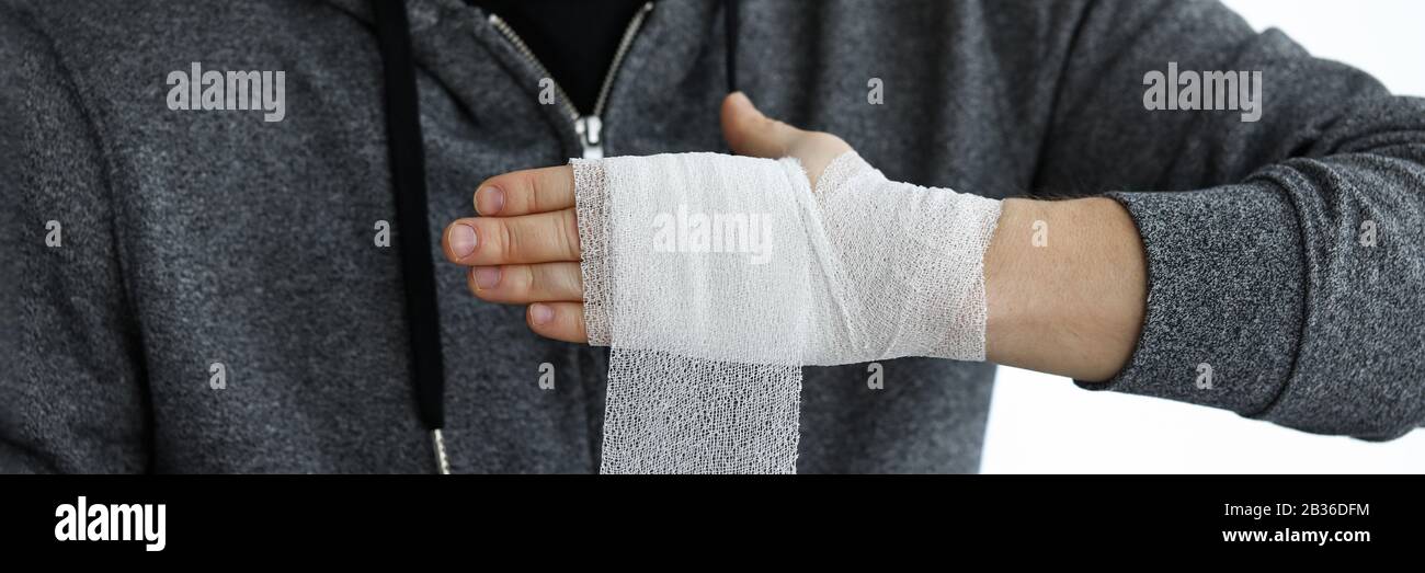 Man give himself first aid rolling bandage tape over wrist Stock Photo
