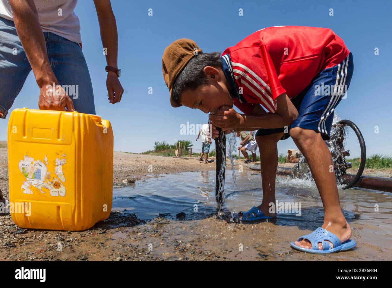 Mongolia, Omnogovi province, near Dalanzadgad, child drinking water from a roadside drain Stock Photo
