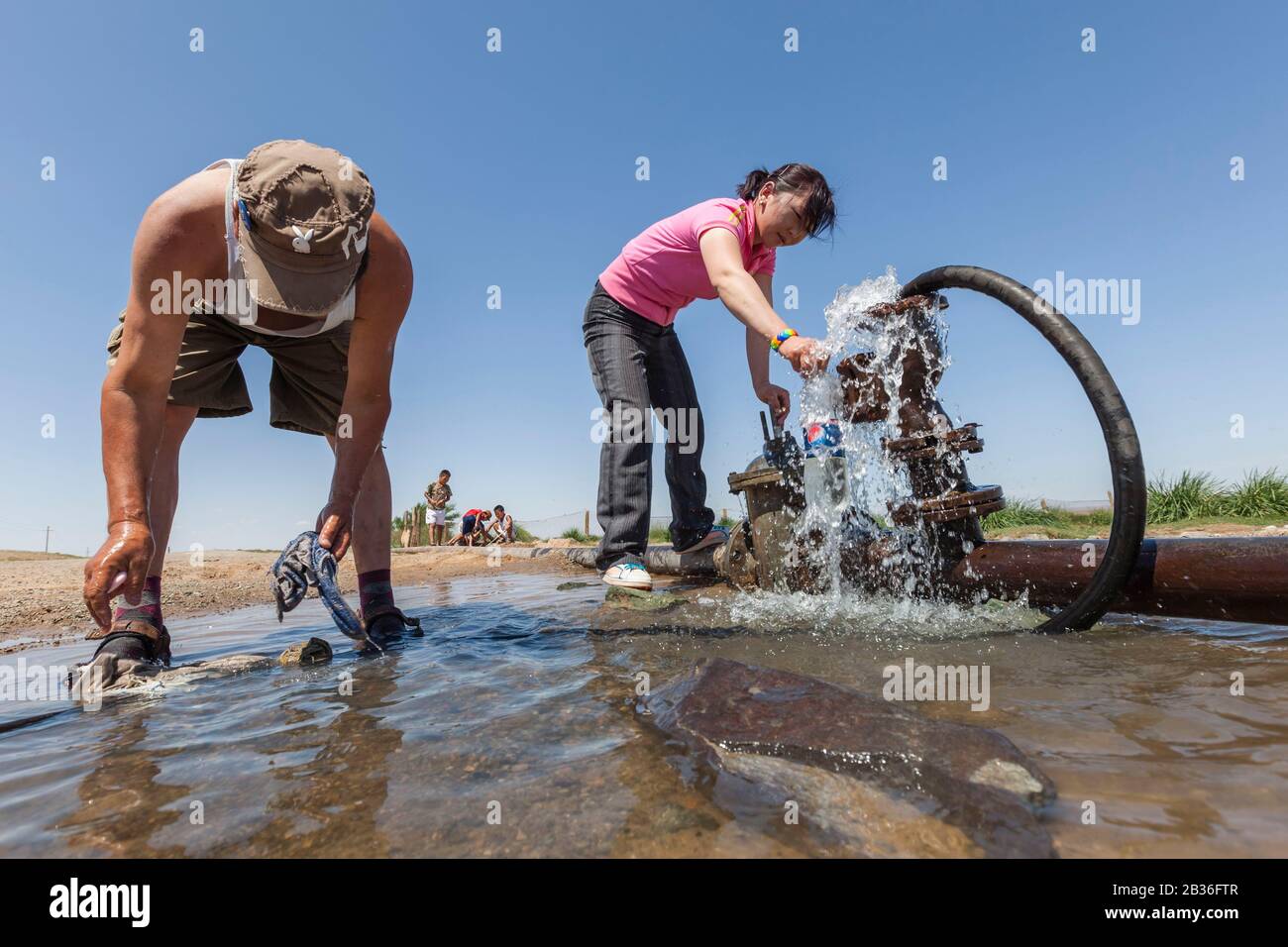 Mongolia, Omnogovi province, near Dalanzadgad, woman filling up a bottle with water from a roadside drain Stock Photo