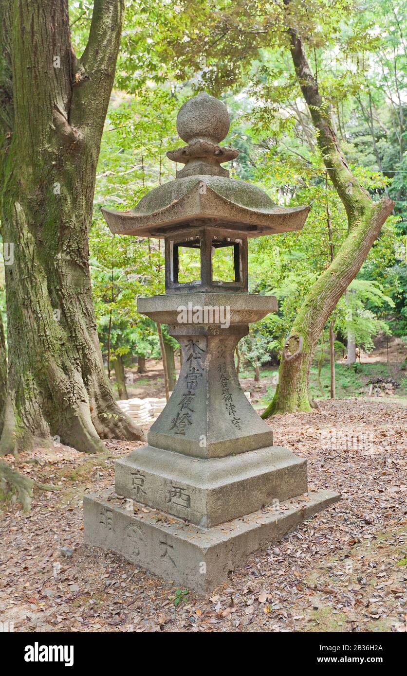 Traditional stone lantern (toro) in Fushimi Inari Taisha Shinto Shrine in Kyoto, Japan. Shrine was founded in 711 and is famous for red torii gates Stock Photo
