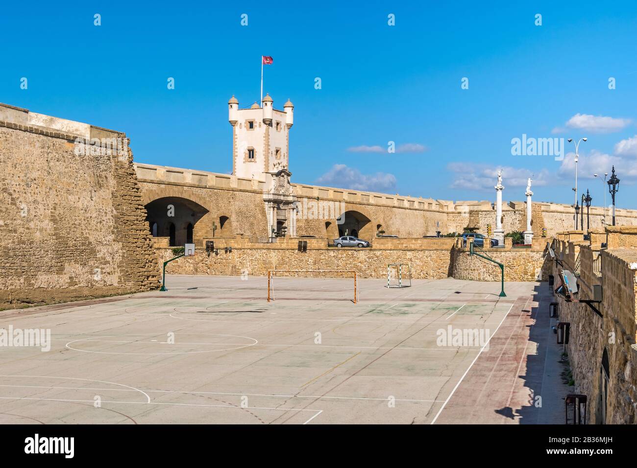 Plaza de la Constitucion with Puertas de Tierra, a bastion-monument built around remnants of the old defensive wall with the purple flag of its canton Stock Photo