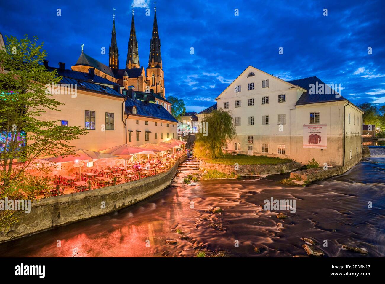 Sweden, Central Sweden, Uppsala, Domkyrka Cathedral with riverfront cafe, dusk Stock Photo