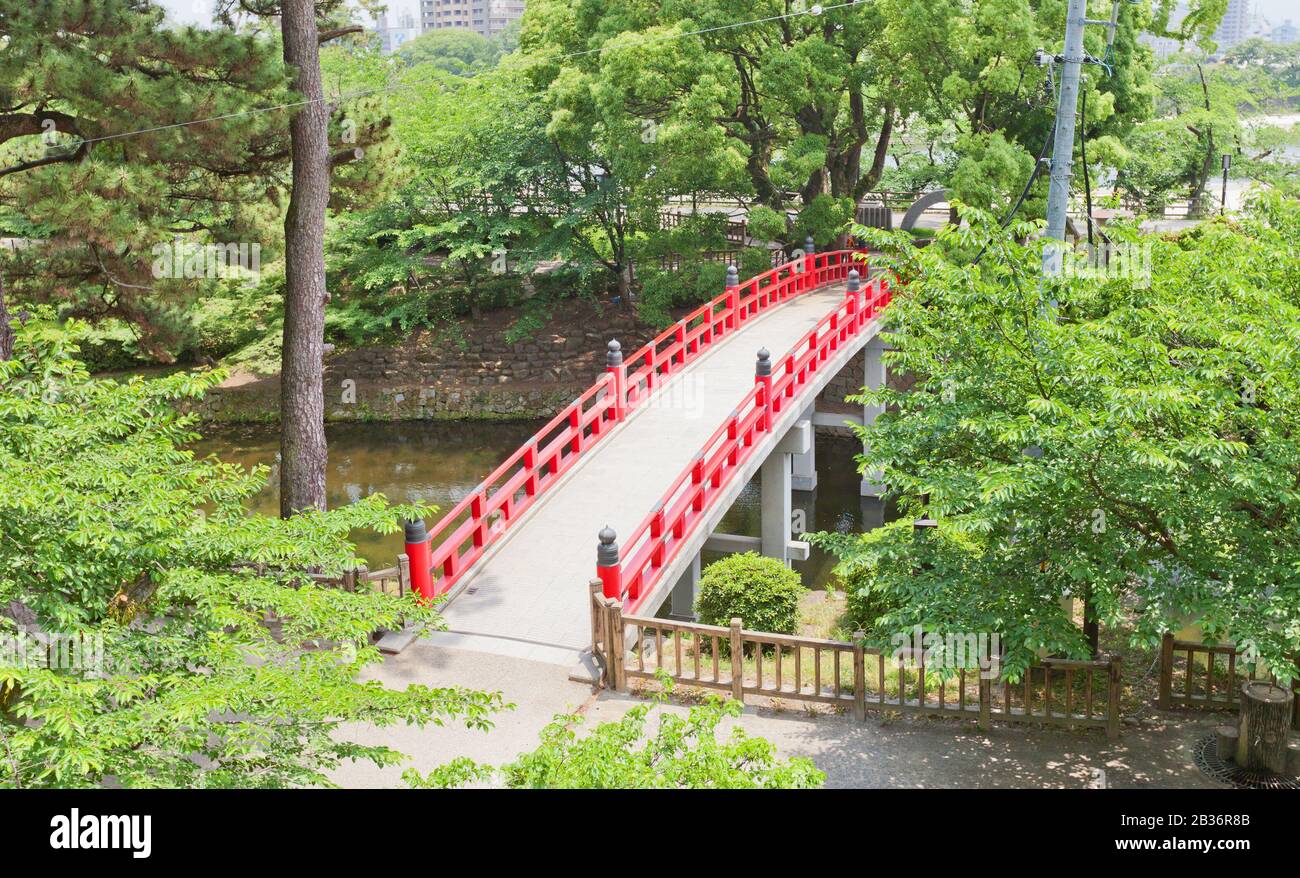 Red bridge over the moat of Okazaki Castle, Japan. Castle was founded in 1455 by Saigo Tsugiyori, shogun Tokugawa Ieyasu was born here in 1543 Stock Photo