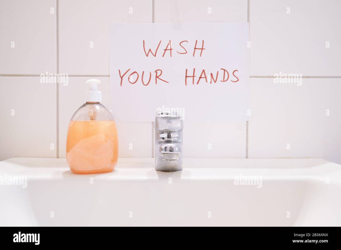 wash your hands - handwritten notice sign above bathroom or restroom sink - hygiene prevents infection Stock Photo